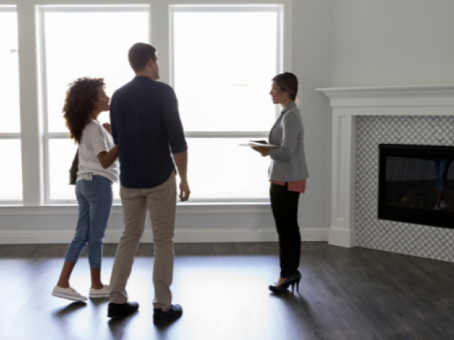 A young couple meets with a realtor in an empty home 