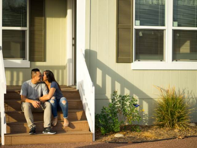 A couple kissing outside on the steps of their home